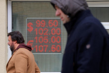 Chodci prechádzajú okolo elektronickej tabule zobrazujúcej výmenné kurzy amerického dolára a eura voči ruskému rubľu na ulici v ruskej Moskve. FOTO: REUTERS