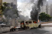 Horiace autá v izraelskom meste Aškelon po tom, ako ich zasiahli rakety vystrelené z pásma Gazy. FOTO: TASR/AP