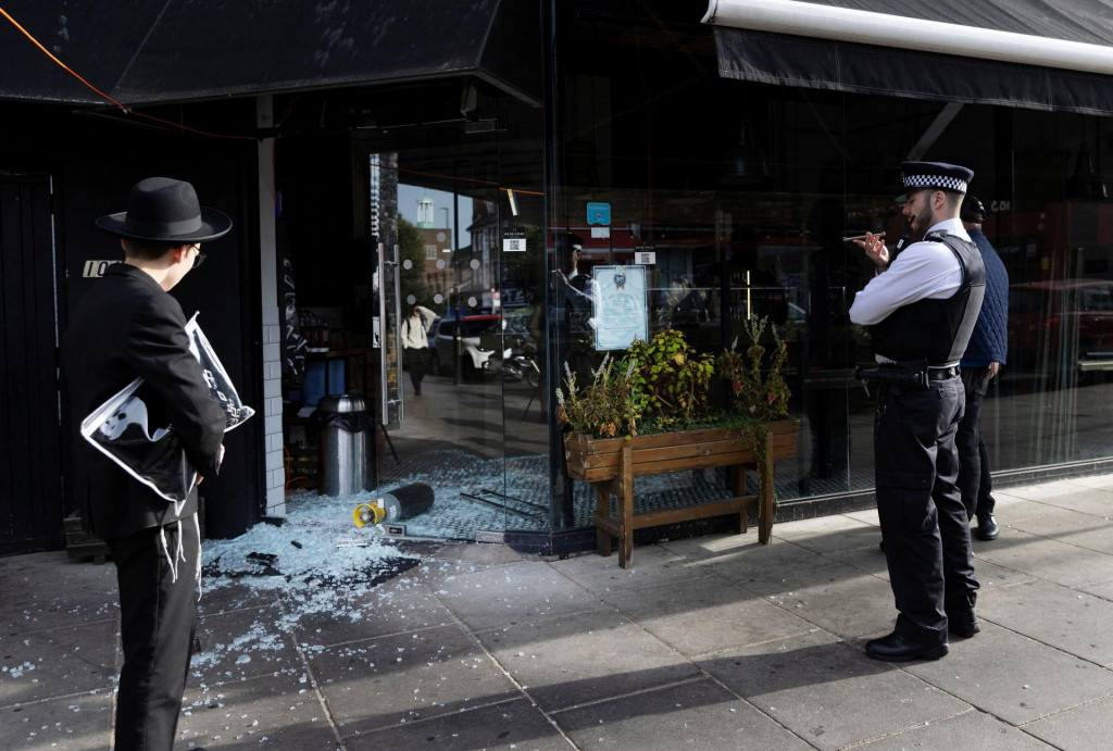 Policajt stojí vedľa zdevastovanej kóšer reštaurácie pri moste s nápisom „Slobodná Palestína“ v Golders Green v Londýne. FOTO: Reuters