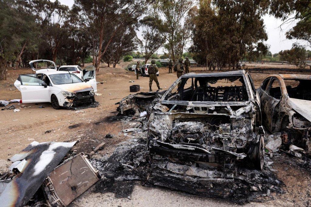 Izraelskí vojaci kontrolujú vraky zhorených áut na mieste konania hudobného festivalu, ktorý napadli islamskí teroristi zanechajúc za sebou minimálne 250 mŕtvych. FOTO: REUTERS