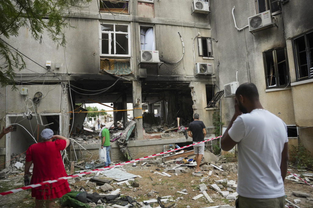 Izraelčania kontrolujú poškodenú obytnú budovu po zásahu raketou vypálenou z pásma Gazy v izraelskom meste Aškelon. FOTO: TASR/AP