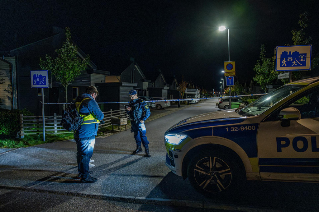 Polícia stojí neďaleko policajnej pásky v Botkyrke neďaleko švédskeho Štokholmu, kde došlo podľa miestnych médií k streľbe. FOTO: REUTERS