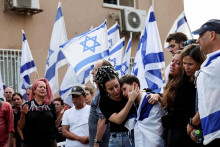 Ľudia držia izraelské vlajky a smútia za Dorom Rederom, ktorý bol zabitý po infiltrácii ozbrojencov Hamasu z pásma Gazy do Izraelu. FOTO: Reuters