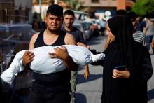 Muž nesie telo palestínskeho dieťaťa zabitého pri izraelských útokoch. FOTO: Reuters