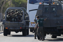 Izraelskí vojaci smerujú na vojenskom aute k horiacemu miestu po raketovom útoku z pásma Gazy na juhu Izraela. FOTO: TASR/AP