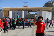 Egyptskí dobrovoľníci sa zhromažďujú a oslavujú s palestínskou vlajkou vedľa nákladných áut s humanitárnou pomocou od egyptských mimovládnych organizácií, ktoré prechádzajú cez priechod Rafah z egyptskej strany. FOTO: Reuters
