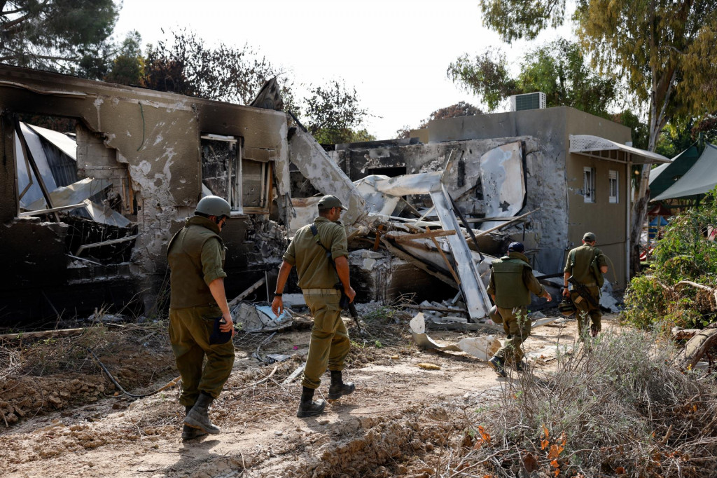 Izraelskí vojaci prechádzajú popri pozostatkoch štruktúr po smrteľnej infiltrácii ozbrojencov Hamasu z pásma Gazy. FOTO: Reuters