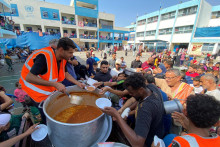 Utečenci z Palestíny sa zhromažďujú, aby dostali svoj podiel na charitatívnom jedle, ktoré ponúkajú dobrovoľníci z OSN v Rafahu v južnom pásme Gazy. FOTO: Reuters