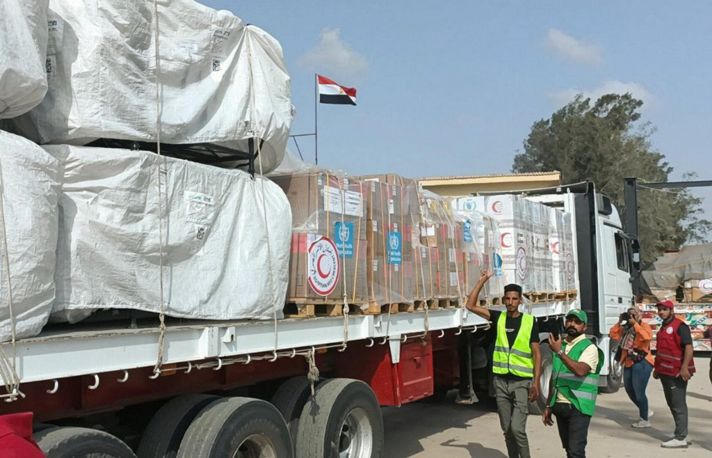Členovia a dobrovoľníci egyptského Červeného polmesiaca sa zhromažďujú vedľa nákladného auta s humanitárnou pomocou, ktoré prechádza cez priechod Rafah. FOTO: Reuters