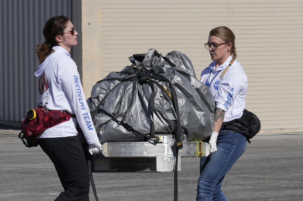 Členky záchranného tímu prenášajú kapsulu s prvými vzorkami z asteroidu Benu do dočasnej čistej miestnosti v Utahu