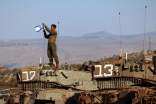 Vojak upevňuje izraelskú vlajku na tank počas cvičenia v blízkosti libanonských hraníc. FOTO: Reuters