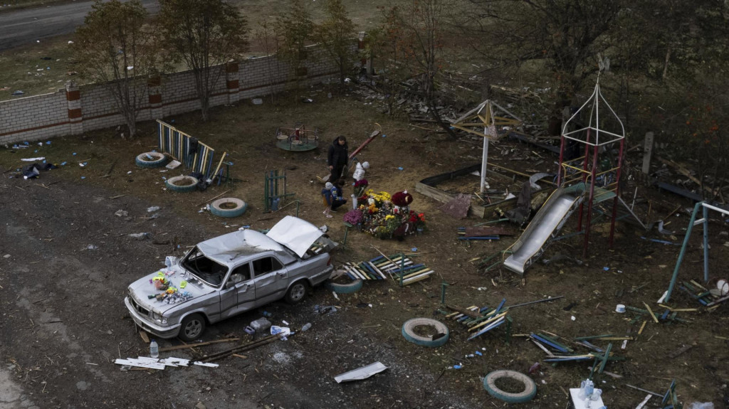 Rodinní príslušníci kladú kvety k pamätníku obetí, ktoré zahynuli po ruskom raketovom útoku na dedinu Hroza v Charkovskej oblasti. FOTO: TASR/AP