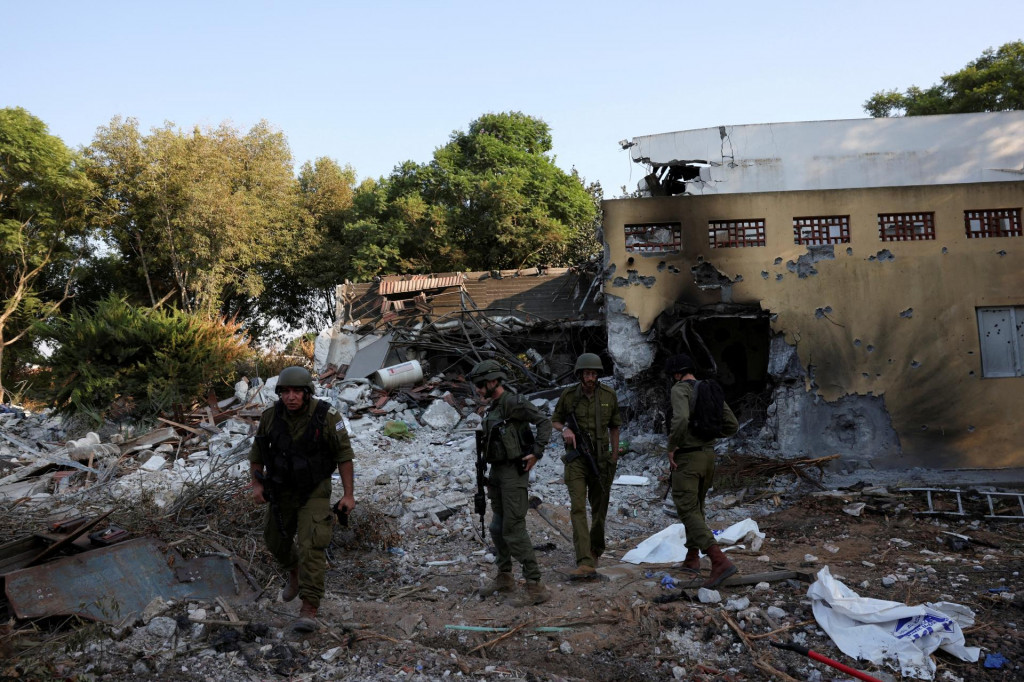 Izraelskí vojaci kráčajú po masovej infiltrácii ozbrojencov Hamasu z pásma Gazy v kibuci Beeri. FOTO: Reuters