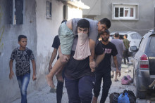 Palestínčan nesie zraneného chlapca po izraelskom leteckom útoku na pásmo Gazy v utečeneckom tábore.