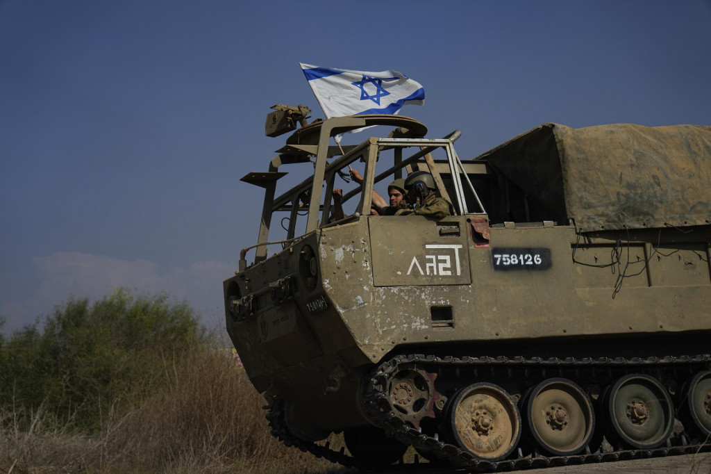 Izraelskí vojaci mávajú národnou vlajkou z tanku, ktorý smeruje k hraniciam pásma Gazy z juhu Izraela. FOTO: TASR/AP
