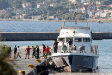 Zachránení migranti vystupujú z plavidla Helénskej pobrežnej stráže v prístave Mytilene.  FOTO: Reuters