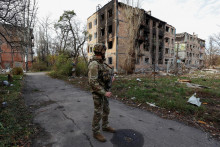 Ukrajinský vojak stojí vedľa obytných budov ťažko poškodených permanentnými ruskými vojenskými útokmi v meste Avdiivka v prvej línii. FOTO: Reuters