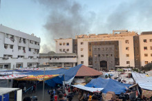 V okolí nemocnice Šifá po explózii stúpa dym, zatiaľ čo Palestínčania hľadajú úkryt. FOTO: Reuters