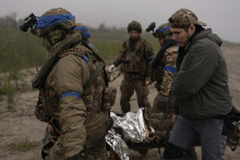 Ukrajinskí vojaci evakuujú zraneného spolubojovníka na frontovej línii neďaleko Dnipra pri Chersone na juhu Ukrajiny. FOTO: TASR/AP
