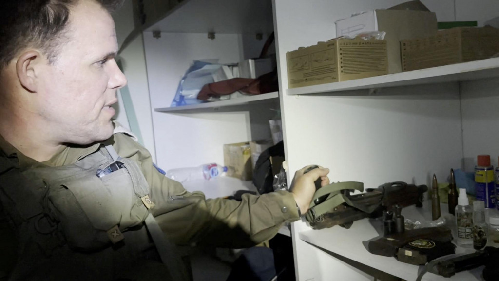 Izraelský dôstojník ukazuje pušku, ktorá bola podľa neho objavená v taške uloženej v skrini so zdravotníckym materiálom v nemocničnom komplexe Al Shifa. FOTO: Reuters