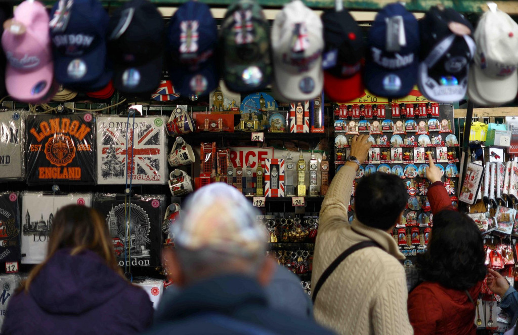 Turisti kupujú predmety v darčekovom stánku v Londýne. FOTO: Reuters