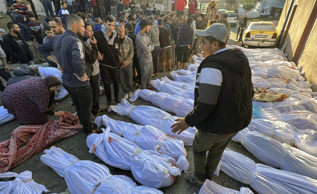 Palestínčania si prezerajú tváre obetí, ktoré prišli o život pri izraelskom bombardovaní utečeneckého tábora Džabálijá v Pásme Gazy. FOTO: TASR/AP