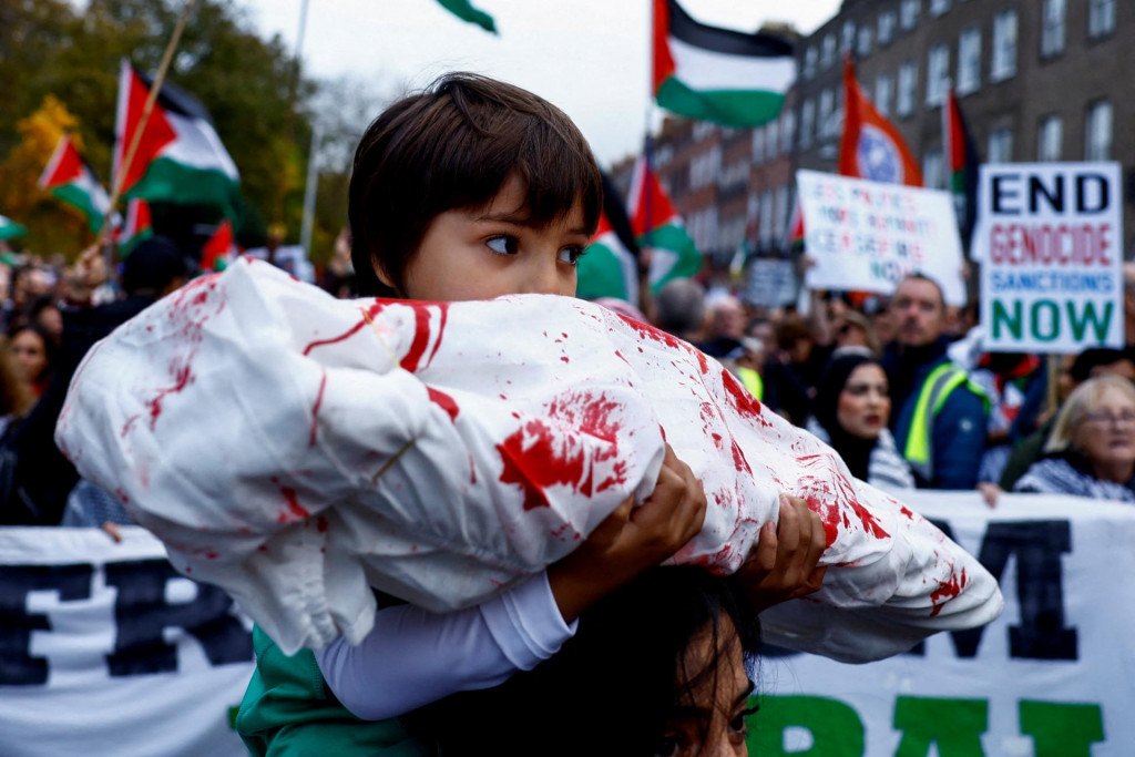 Dieťa drží falošné telo zabalené v látke počas dublinského protestu solidarity s Palestínčanmi v Gaze. FOTO: Reuters