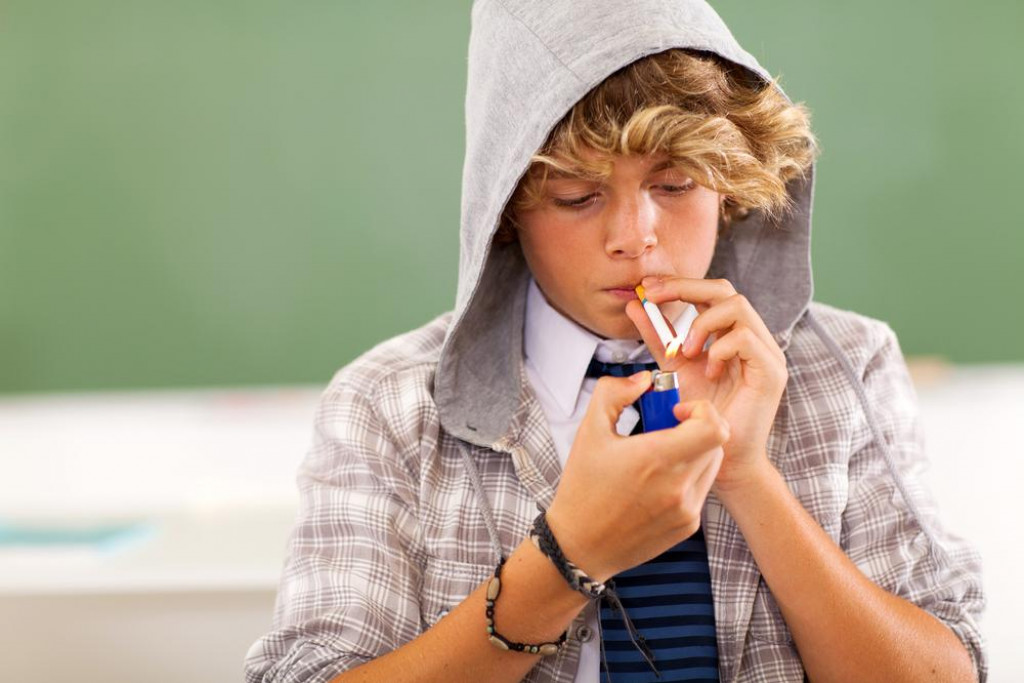 bad high school teen boy lighting cigarette in classroom