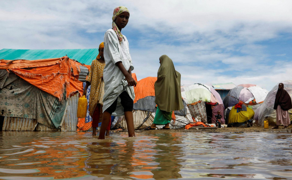 Obyvatelia sa brodia záplavovou vodou v provizórnych prístreškoch v tábore Al-Hidaya pre vnútorne vysídlené osoby po silných dažďoch na predmestí Mogadiša. FOTO: Reuters