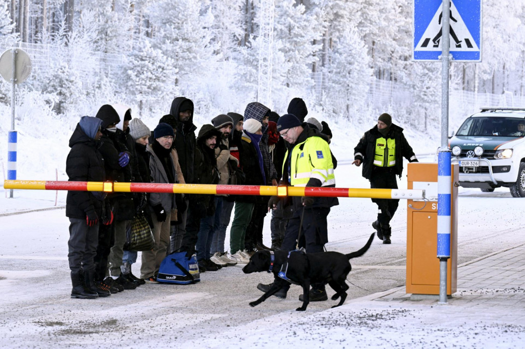 Migranti sa pozerajú na psa fínskeho colného úradníka na medzinárodnom hraničnom priechode v Salle v severnom Fínsku. FOTO: REUTERS