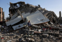 Palestínčan sedí medzi troskami domu zničeného pri izraelskom útoku. FOTO: Reuters