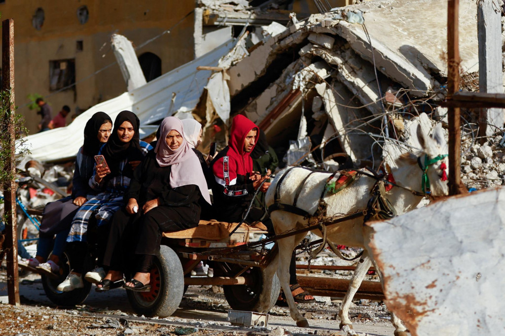 Vysídlení Palestínčania jazdia na vozíku ťahanom zvieratami v blízkosti domov zničených pri izraelskom útoku. FOTO: Reuters