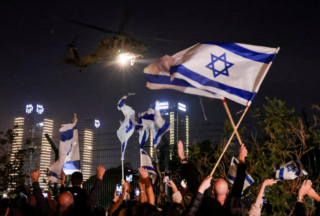 Ľudia mávajú izraelskými vlajkami, keď helikoptéra prichádza s rukojemníkmi prepustenými v rámci dohody medzi Izraelom a palestínskym islamistickým hnutím Hamas. FOTO: Reuteres