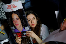 Žena drží transparent počas toho, ako čo ľudia čakajú na správy o rukojemníkoch v izraelskom Tel Avive. FOTO: REUTERS