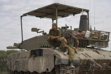 Izraelskí vojaci sedia na tanku v armádnej zóne. FOTO: TASR/AP