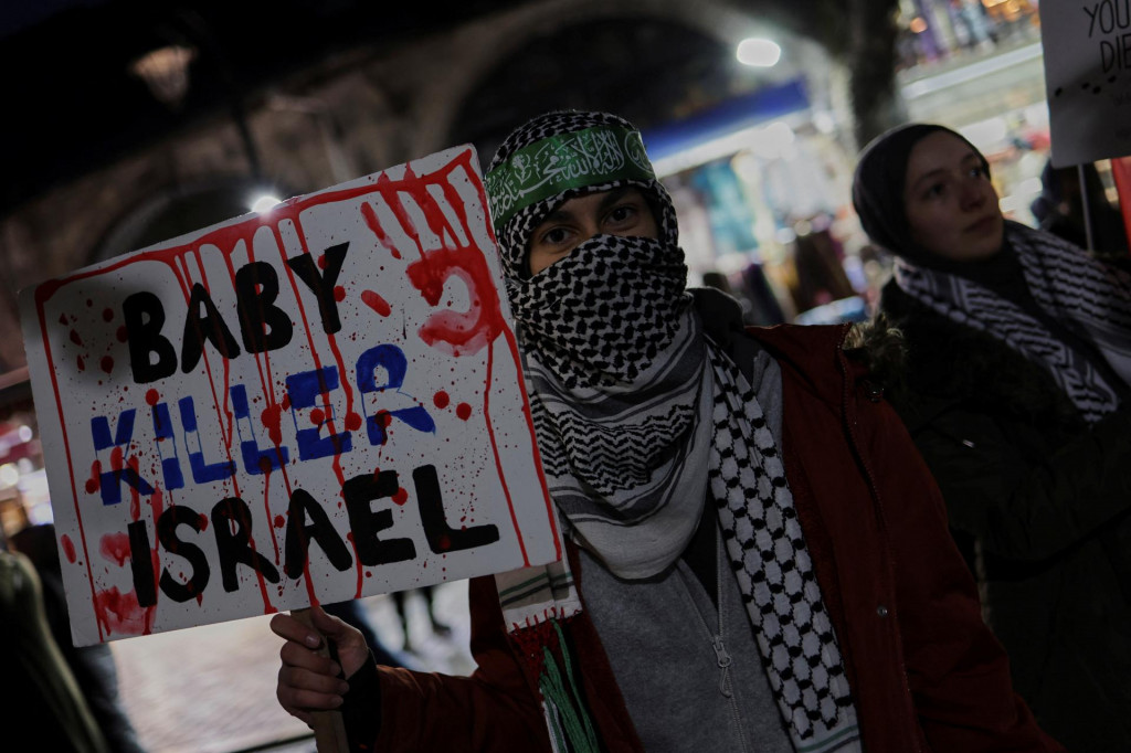 Demonštrant na znak solidarity s Palestínčanmi v Gaze drží transparent v Istanbule. FOTO: Reuters
