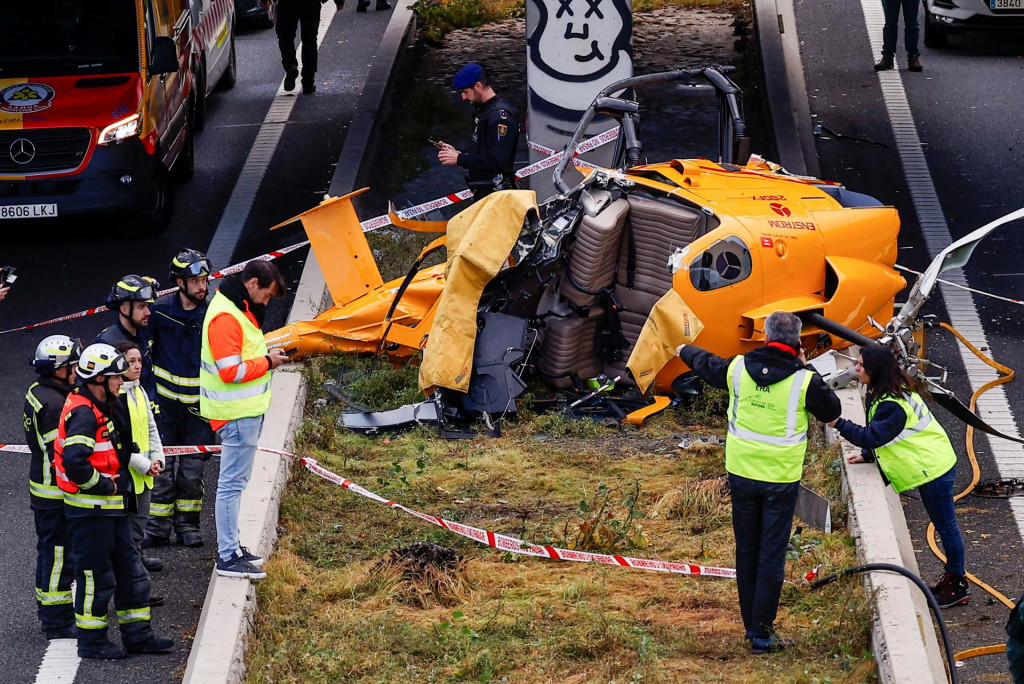 Záchranári stojaci vedľa vrtuľníka, ktorý sa zrútil na diaľničnom obchvate v Madride. FOTO: Reuters