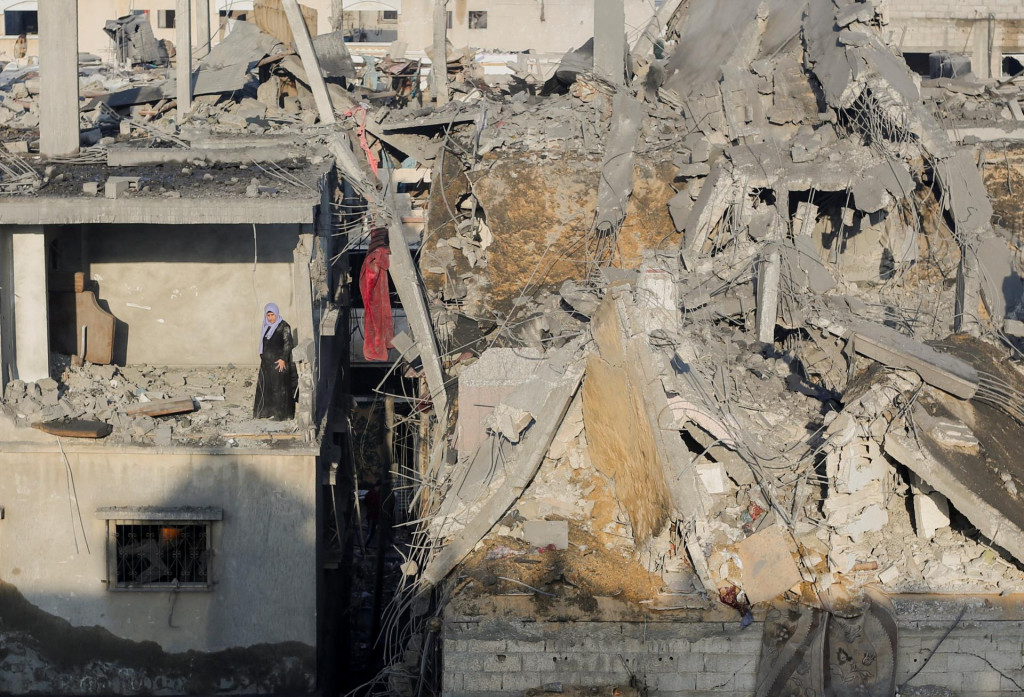 Palestínska žena stojí v zničenej miestnosti v budove a kontroluje miesto izraelských útokov. FOTO: Reuters