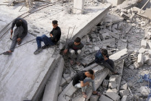 Palestínčania sedia na zničenej budove, ktorá patrila rodine Al-Nadi po izraelskom bombardovaní pásma Gazy v utečeneckom tábore v meste Nusseirat. FOTO: TASR/AP
