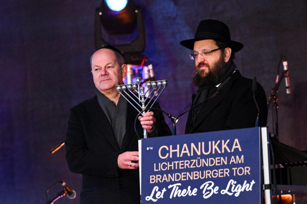 Predseda židovského vzdelávacieho centra Chabad, rabín Jehuda Teichtal, odovzdáva svietnik s menorou nemeckému kancelárovi Olafovi Scholzovi. FOTO: REUTERS