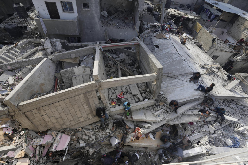Palestínčania prehľadávajú trosky zničenej budovy, ktorá patrila rodine Al-Hor po izraelskom bombardovaní pásma Gazy v utečeneckom tábore v meste Nusseirat. FOTO: TASR/AP