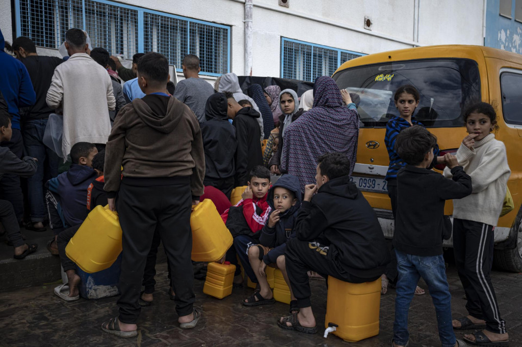 Palestínčania vysídlení v dôsledku izraelského bombardovania Pásma Gazy stoja v rade na vodu vo vysídľovacom tábore OSN v meste Chán Júnis v južnej časti Pásma Gazy. FOTO: TASR/AP
