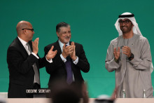 Prezident COP28 Sultán Ahmad al-Džábir tlieska s výkonným riaditeľom COP28 Adnanom Aminom a klimatickým šéfom OSN Simonom Stiellom po dohode na odklone od fosílnych palív. FOTO: TASR/AP