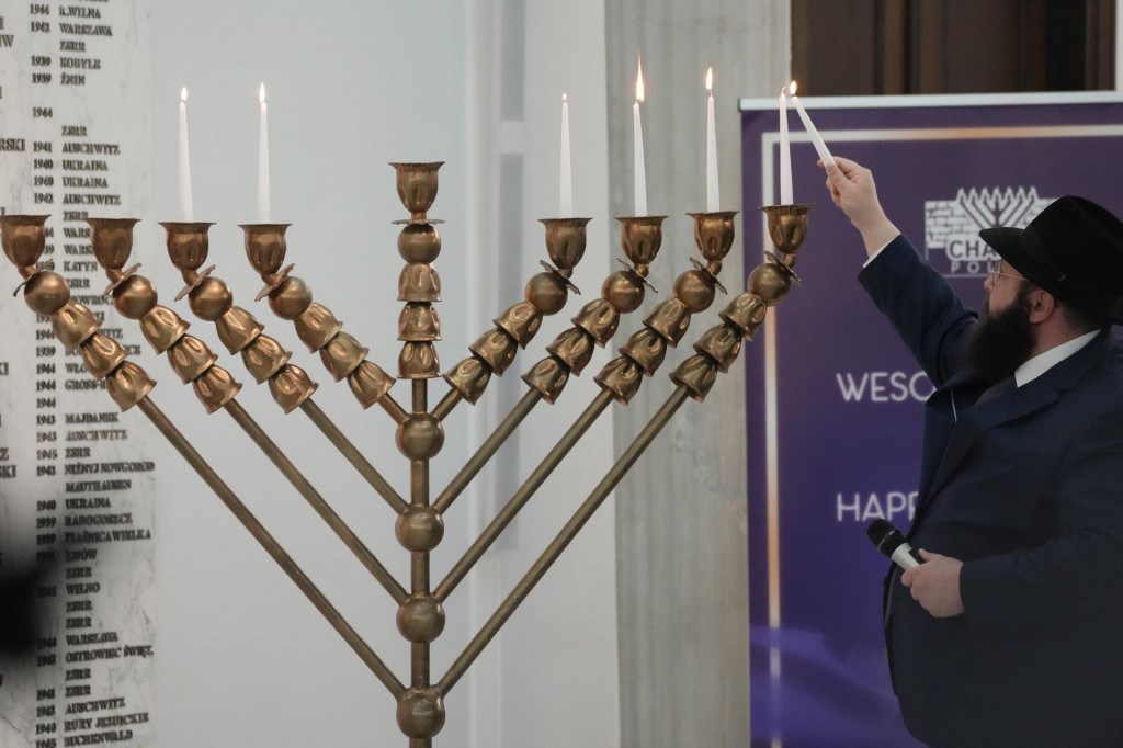 Rabín zapaľuje sviečky na chanukovej menore - deväťramennom svietniku, ktorý sa zapaľuje počas osemdňového židovského sviatku svetiel v poľskom parlamente vo Varšave. FOTO: TASR/AP