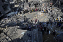 Palestínčania sa pozerajú na trosky zničenej budovy, ktorá patrila rodine Al-Gatshan po izraelskom bombardovaní pásma Gazy v utečeneckom tábore v meste Nusseirat. FOTO: TASR/AP