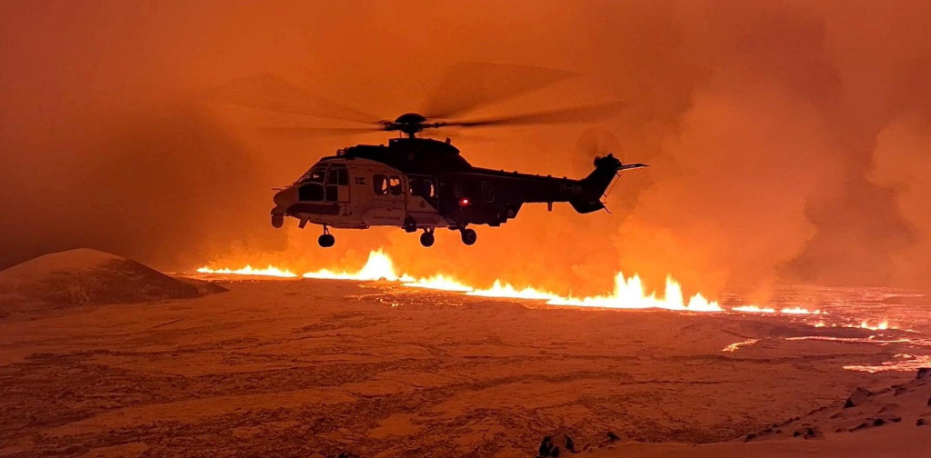 Helikoptéra letí blízko sopky chrliacej lávu a dym pri jej erupcii neďaleko Grindaviku na Islande. FOTO: Reuters