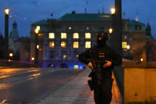 Policajt hliadkuje na moste ponad Vltavu neďaleko budovy Filozofickej fakulty Univerzity Karlovej po streľbe v centre Prahy. FOTO: TASR/AP
