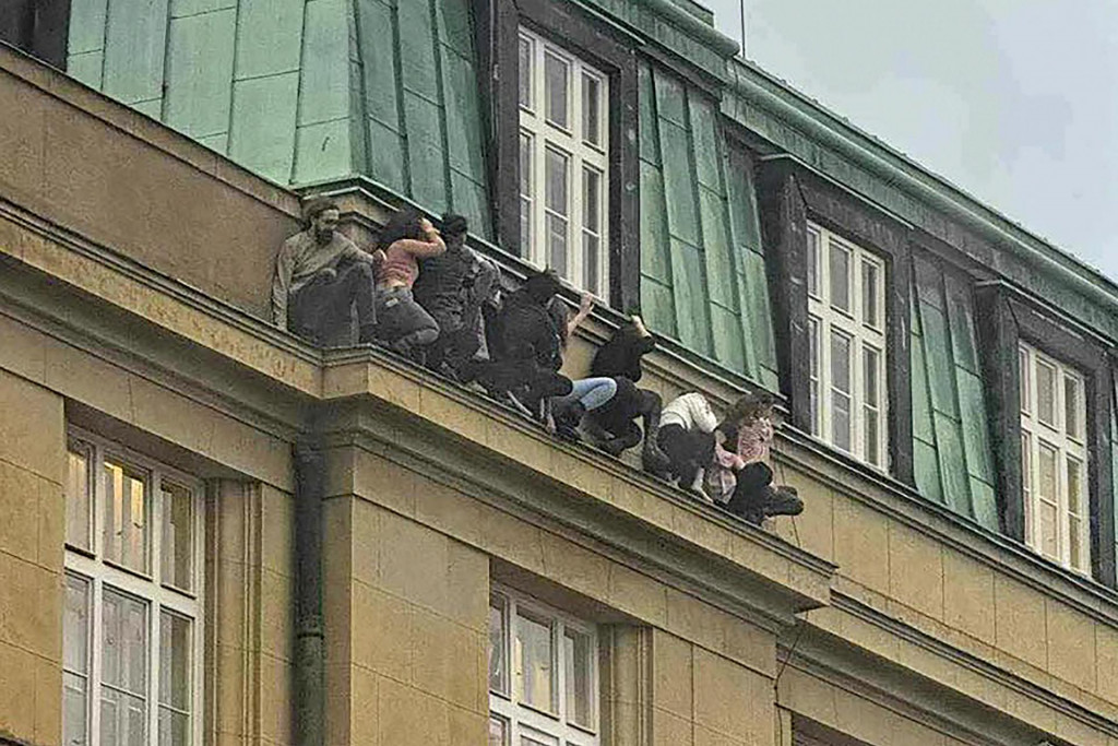 Študenti stoja na rímse budovy Filozofickej fakulty Karlovej univerzity počas streľby v centre Prahy. FOTO: TASR/AP