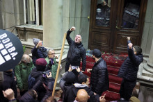 Opozičný líder Aleksandar Jovanovič Cuta gestikuluje počas toho, ako policajti držia dvere radnice počas protestu prívržencov opozície v srbskom Belehrade. FOTO: REUTERS