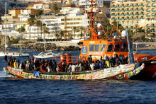 Skupinu migrantov na drevenom člne odťahuje španielske plavidlo pobrežnej stráže do prístavu Arguineguin na ostrove Gran Canaria. FOTO: Reuters